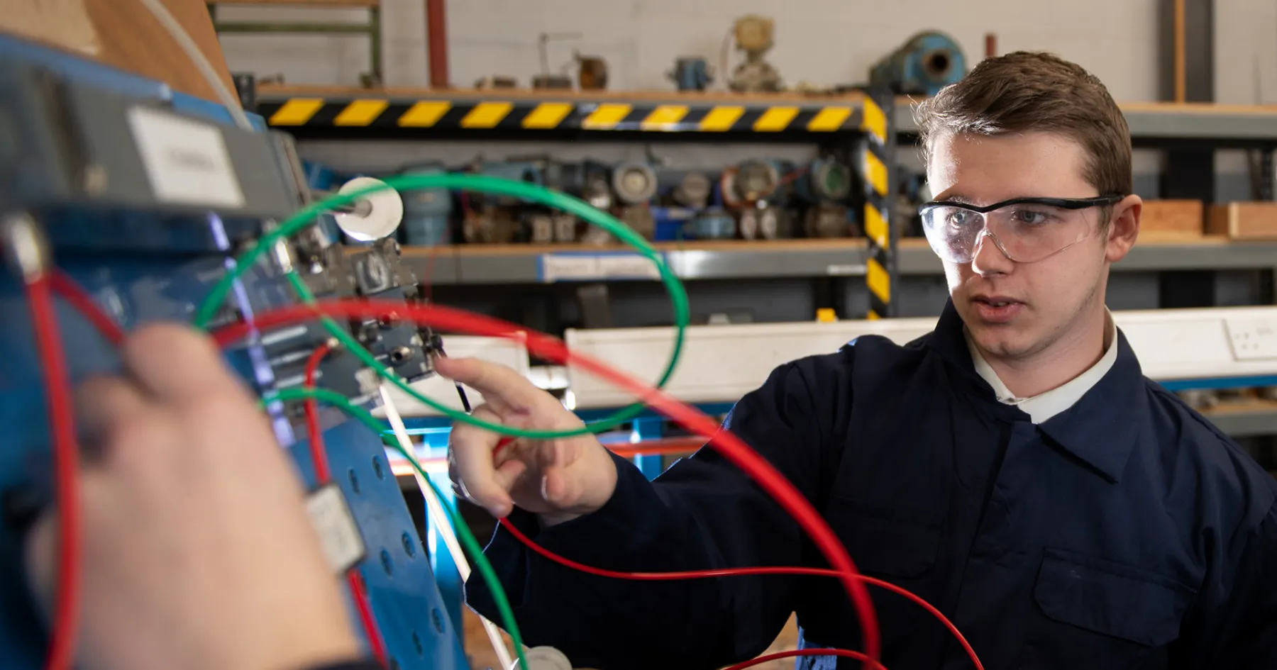 An apprentice pointing at some wiring